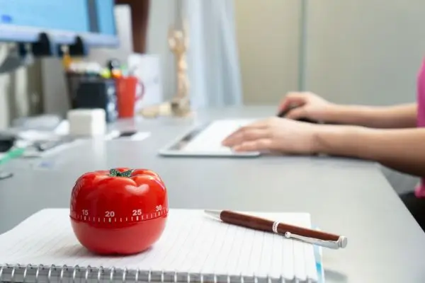 Mesa de escritório com o timer de tomate para por em prática a Técnica de Pomodoro.